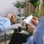 *"Woman lying on a couch during a therapy session, while the therapist takes notes."*